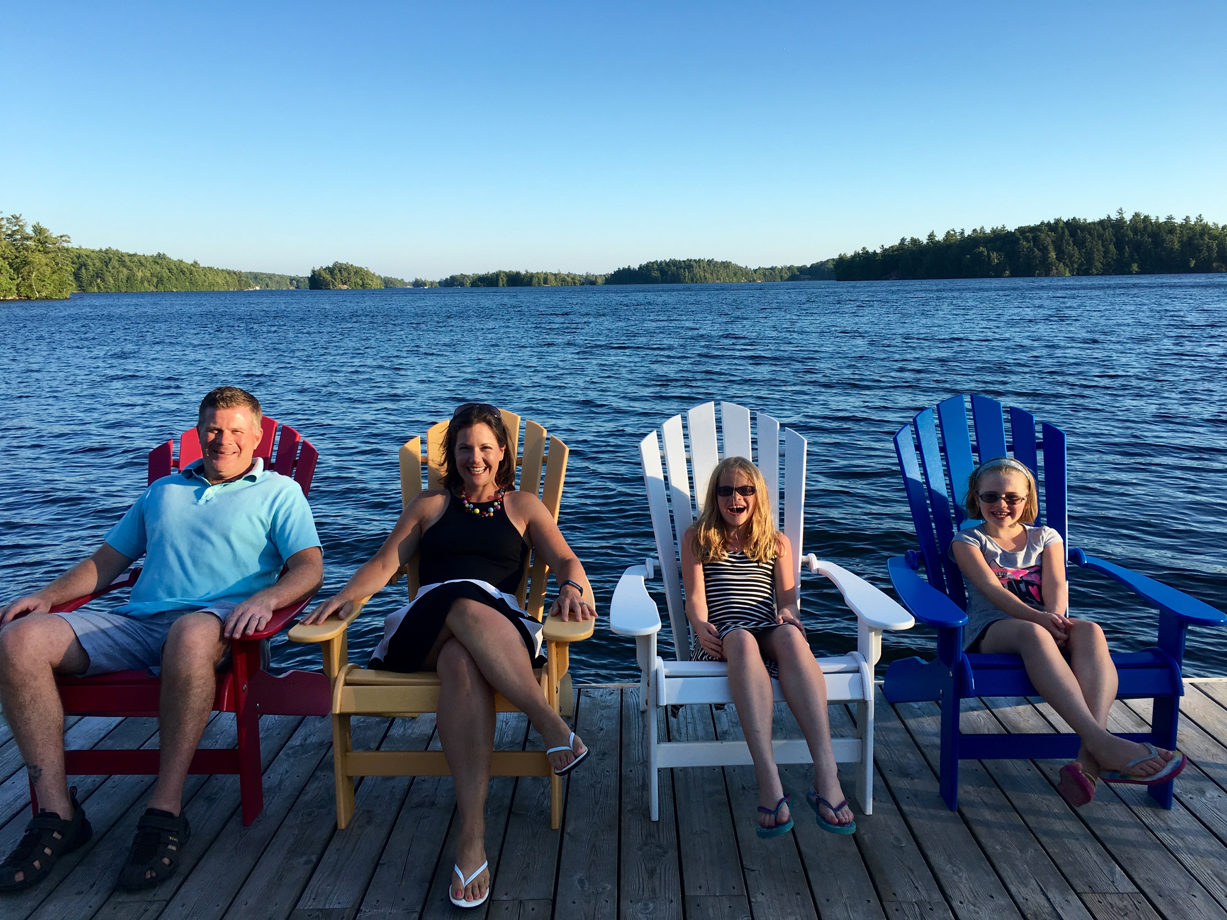 Image of a family sitting in Muskoka chairs on the waterfront