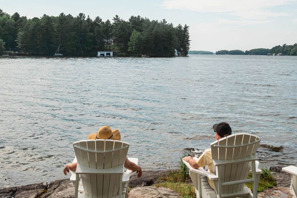 Image of a couple sitting in Muskoka chairs by the water