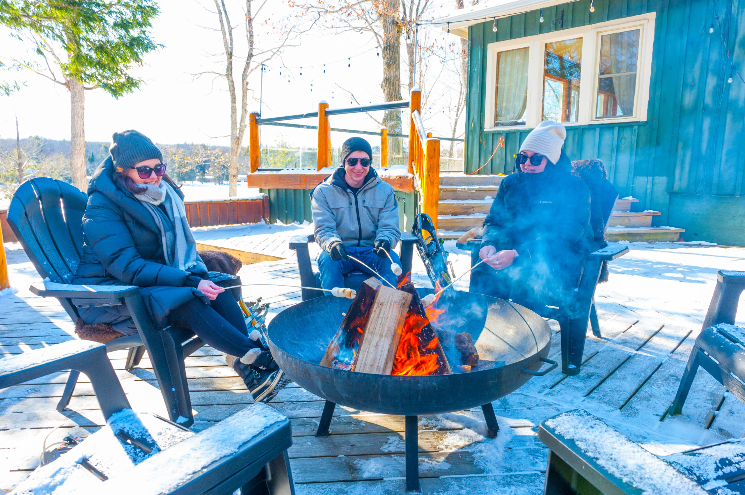 Couple sitting around a fire outdoor in the winter time at Heather Lodge - Resorts of Ontario